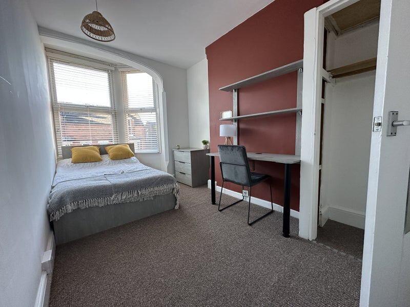 A bright double bedroom featuring a comfortable...