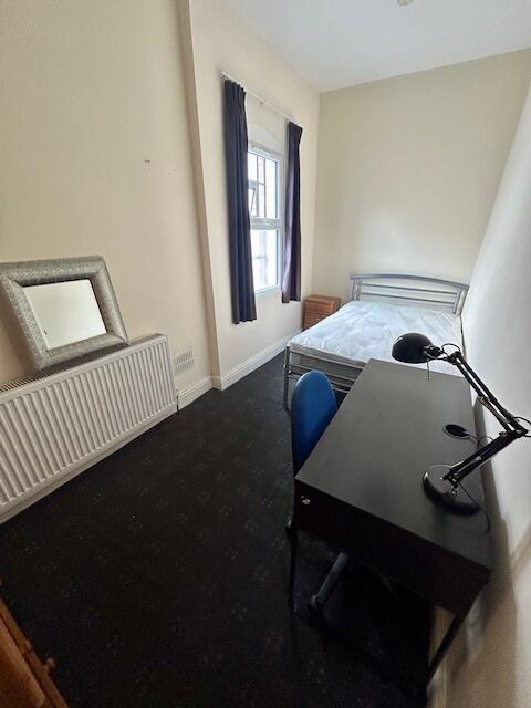 A neat and tidy single bedroom featuring a sing...