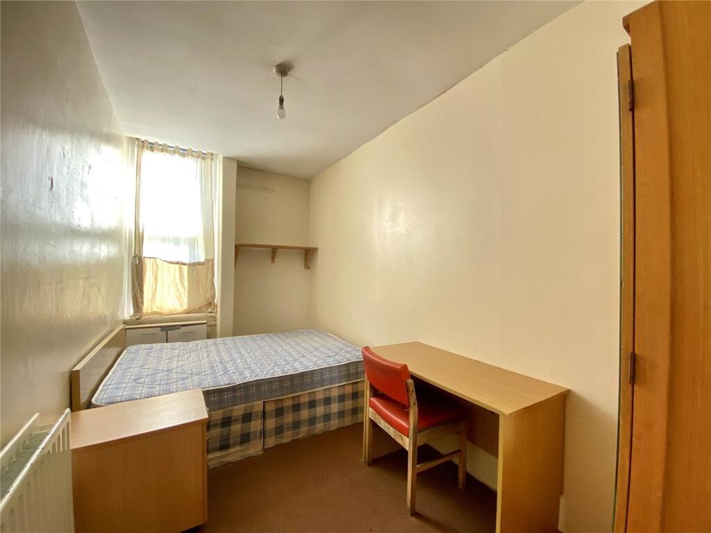 A cozy single bedroom with a neat bed, wooden d...