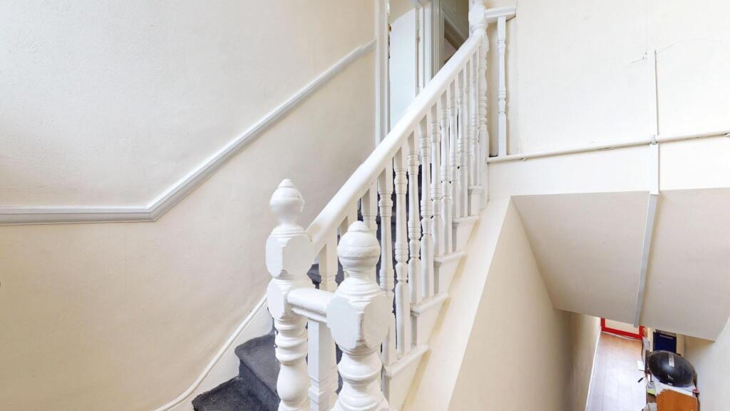 Bright and clean staircase with white wooden ba...