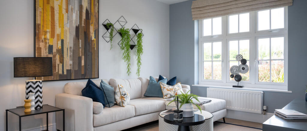 Modern living room with white sofa, colourful cushions, large window, and decorative wall art and pl