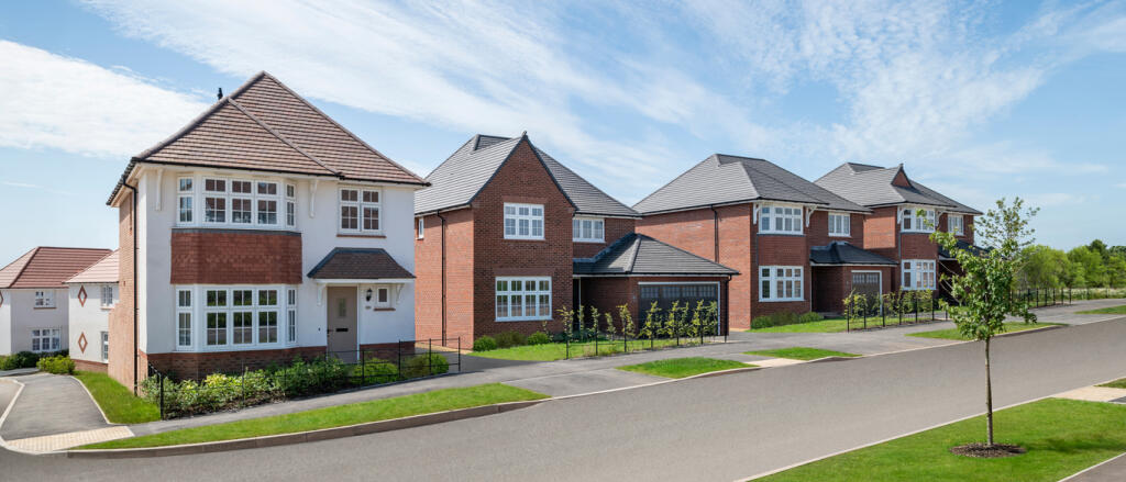 Modern suburban houses with red and grey brick exteriors, well-maintained lawns and driveways on a b