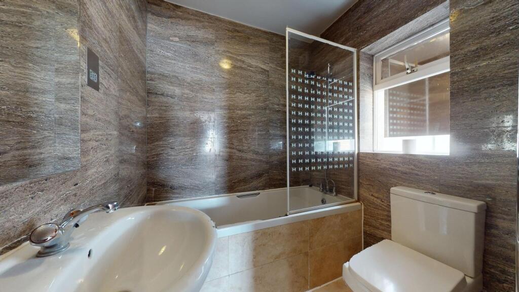 Modern bathroom featuring a bathtub with a glas...