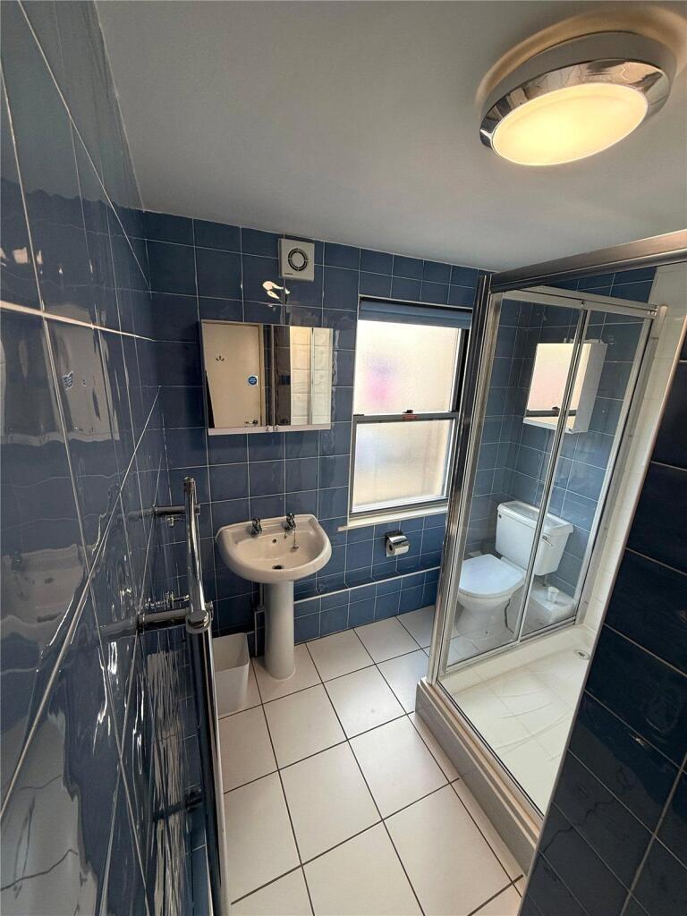 A modern bathroom featuring blue tiled walls, a...