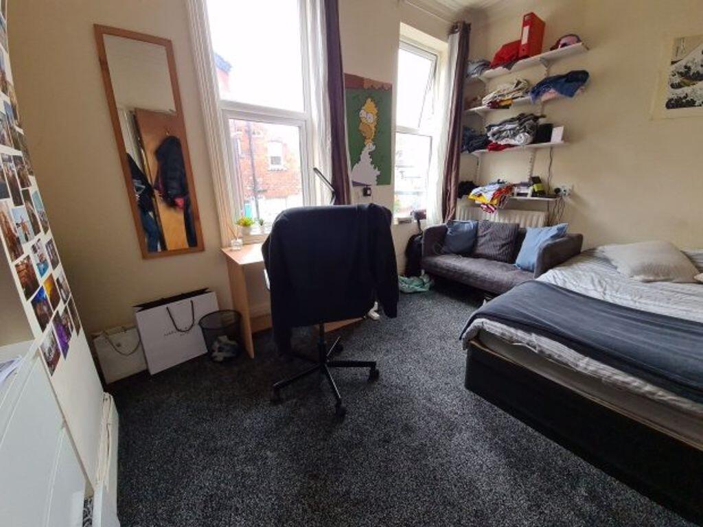 A cozy bedroom featuring a bed, desk, and shelv...