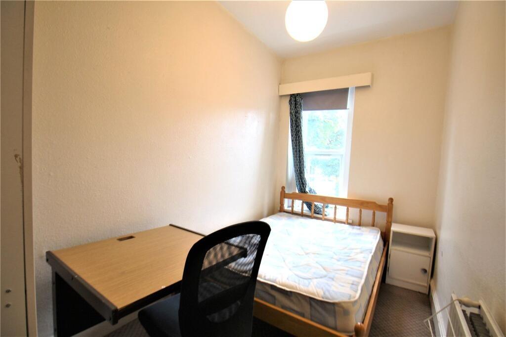 A neat single bedroom featuring a simple wooden...