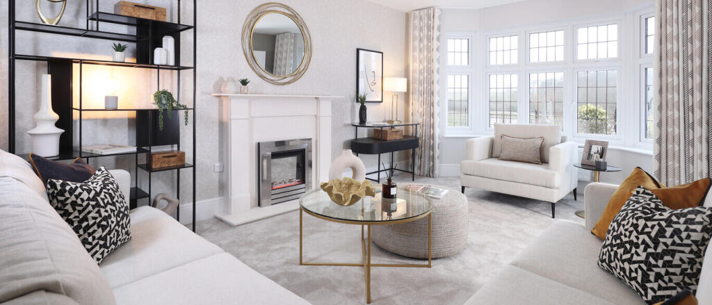Modern living room with green walls, cream sofa, dark green armchair, gold side tables, and large wi