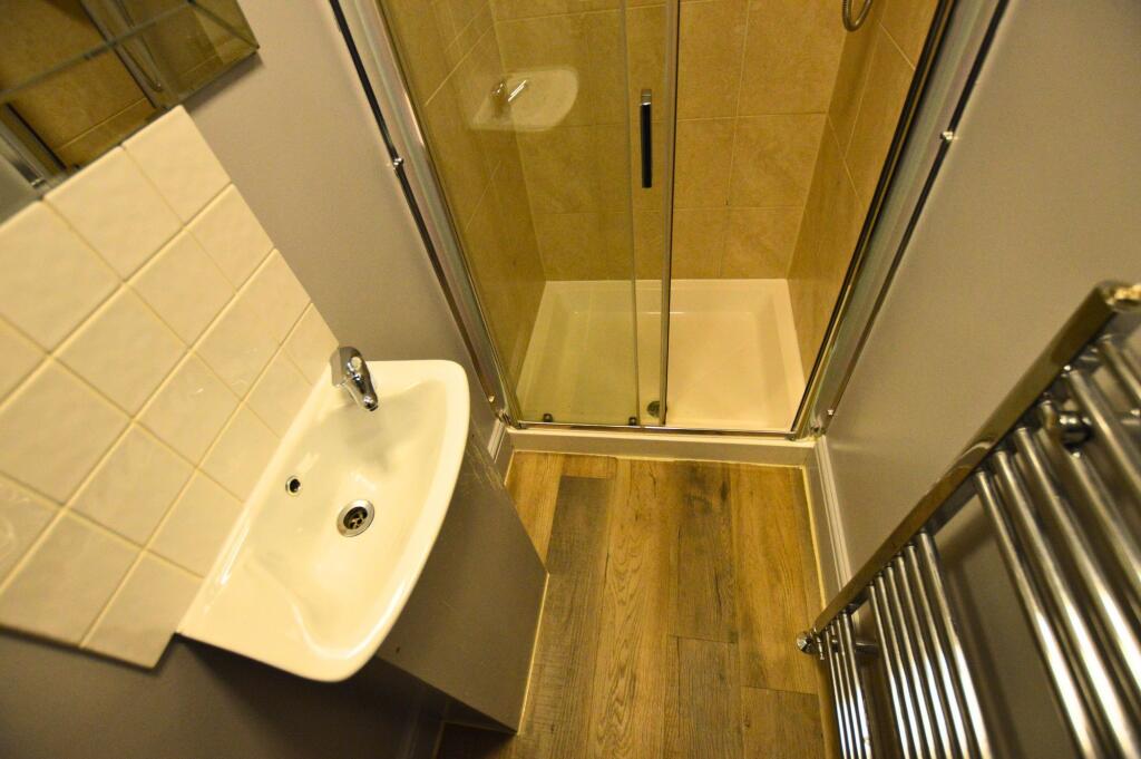 A compact, modern bathroom featuring a glass-en...