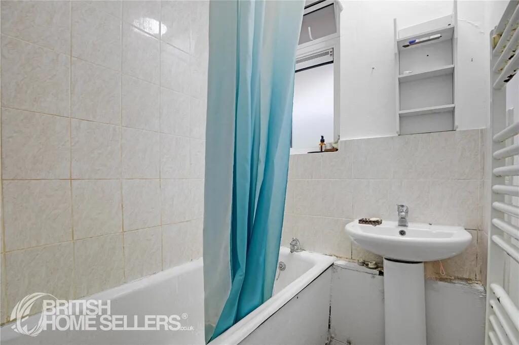 A compact bathroom featuring a white bathtub wi...