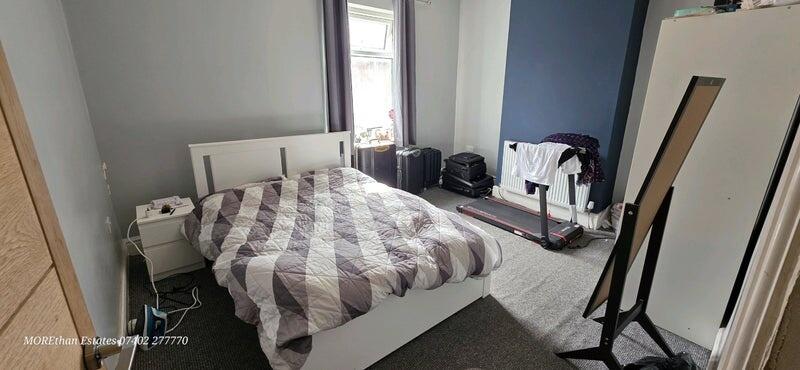 A well-lit double bedroom featuring a comfortab...