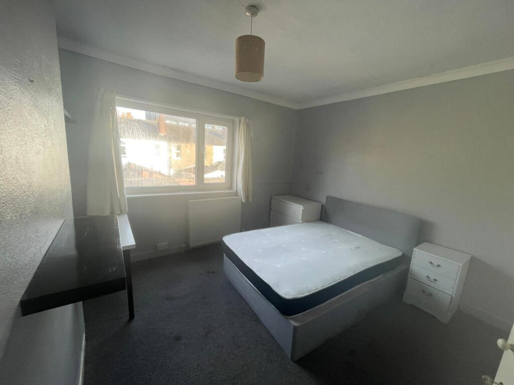 A simple bedroom with a window providing natura...