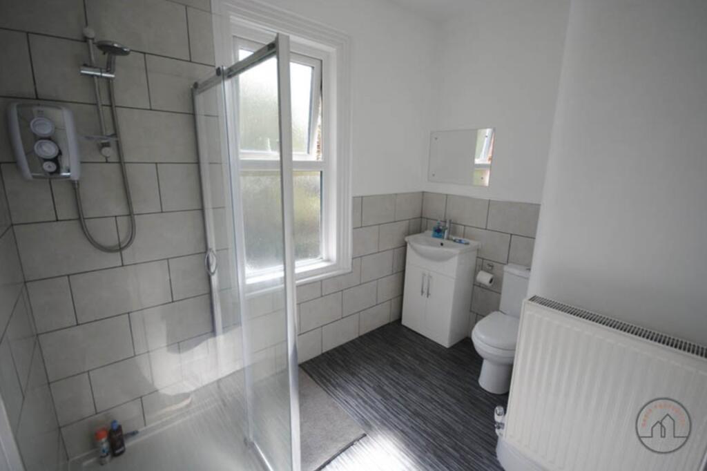 A clean and modern bathroom with a shower unit,...