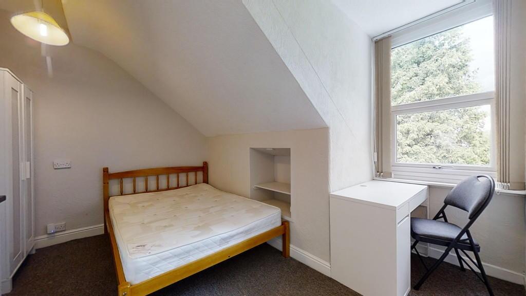 Cozy single bedroom featuring a comfortable woo...