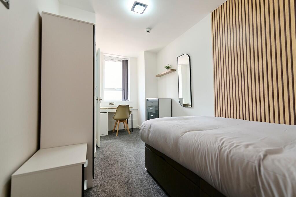 A neat and modern single bedroom with a cozy be...