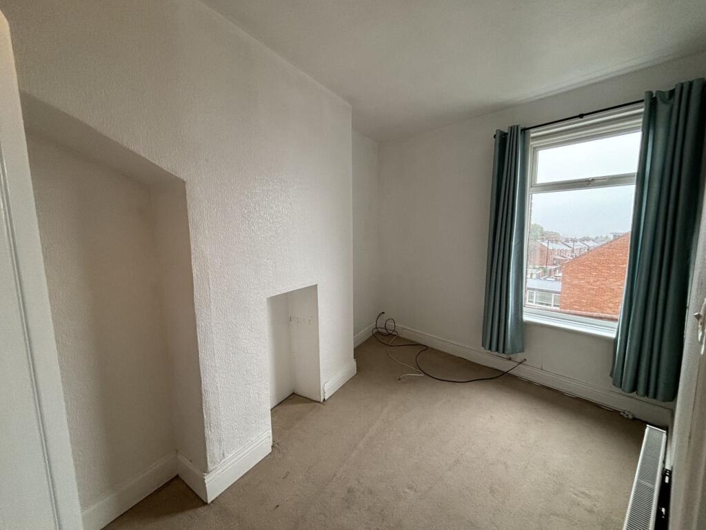 A cozy single bedroom with a large window drape...