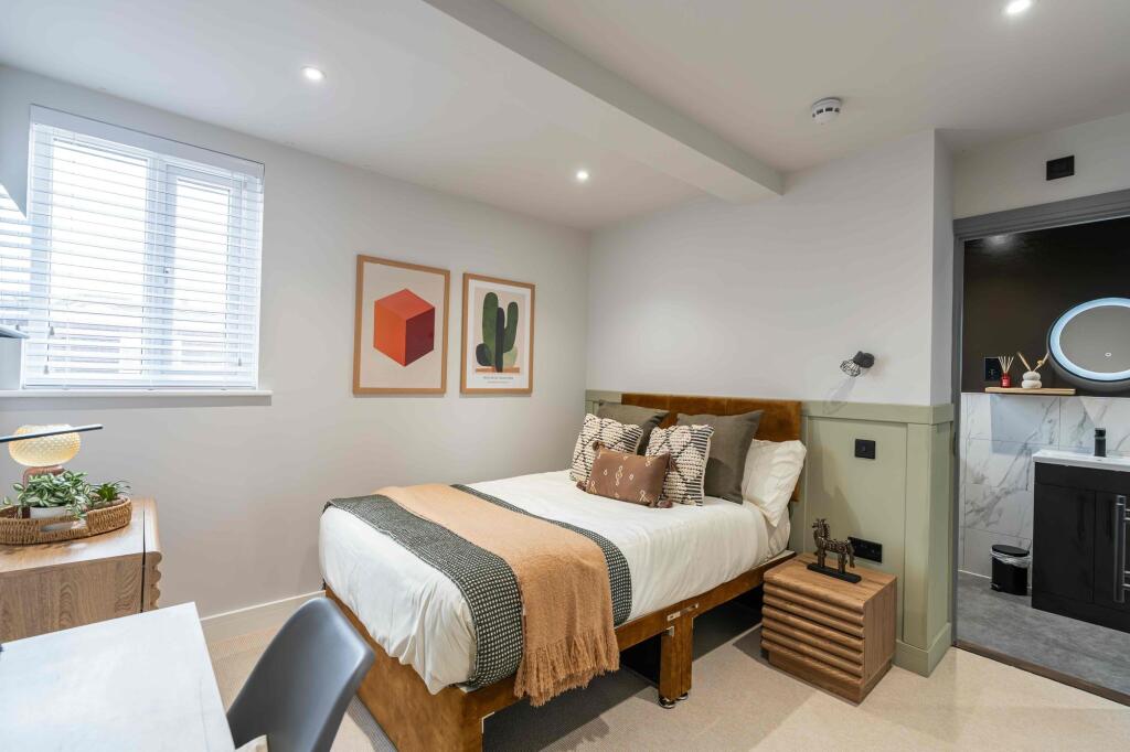 A bright and stylish double bedroom featuring a...