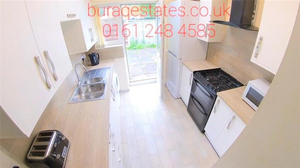 Bright, modern galley kitchen with light wood w...