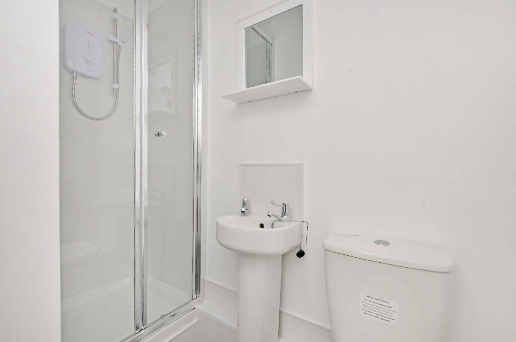 A clean, modern bathroom featuring a shower enc...