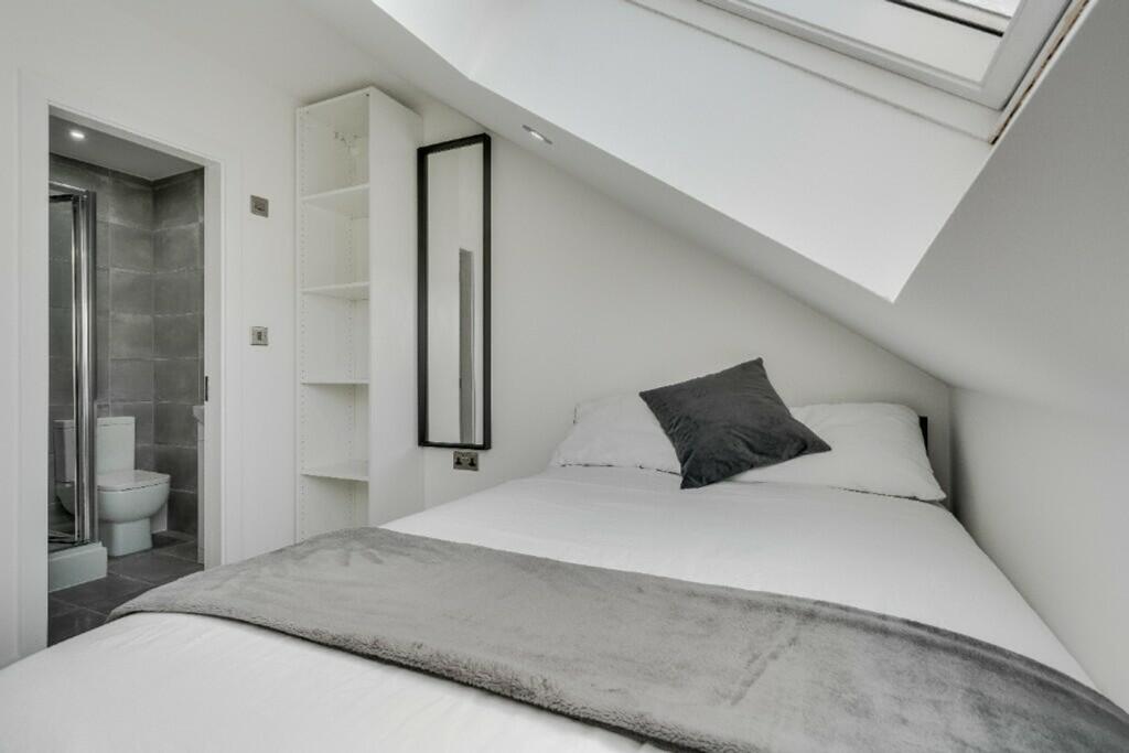 A bright and modern double bedroom featuring an...