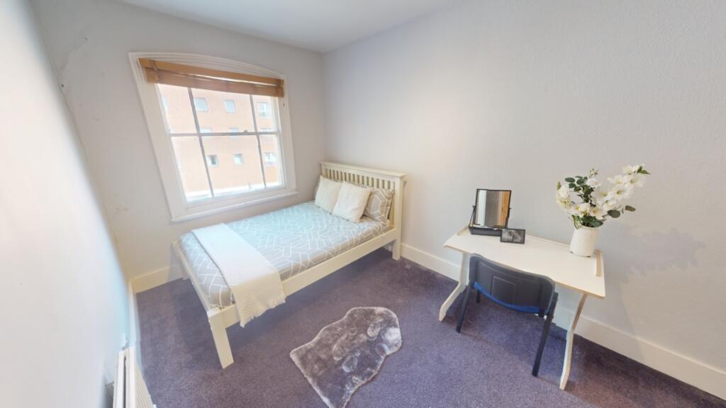 A bright, tidy single bedroom featuring a comfo...