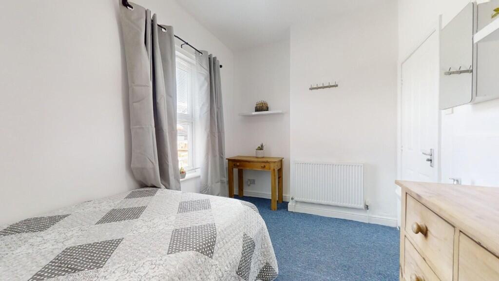 A bright and tidy single bedroom featuring a co...