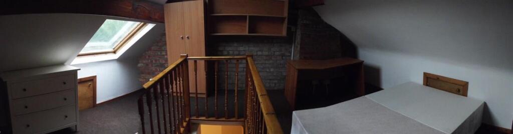 Spacious attic bedroom with sloped ceilings, a ...