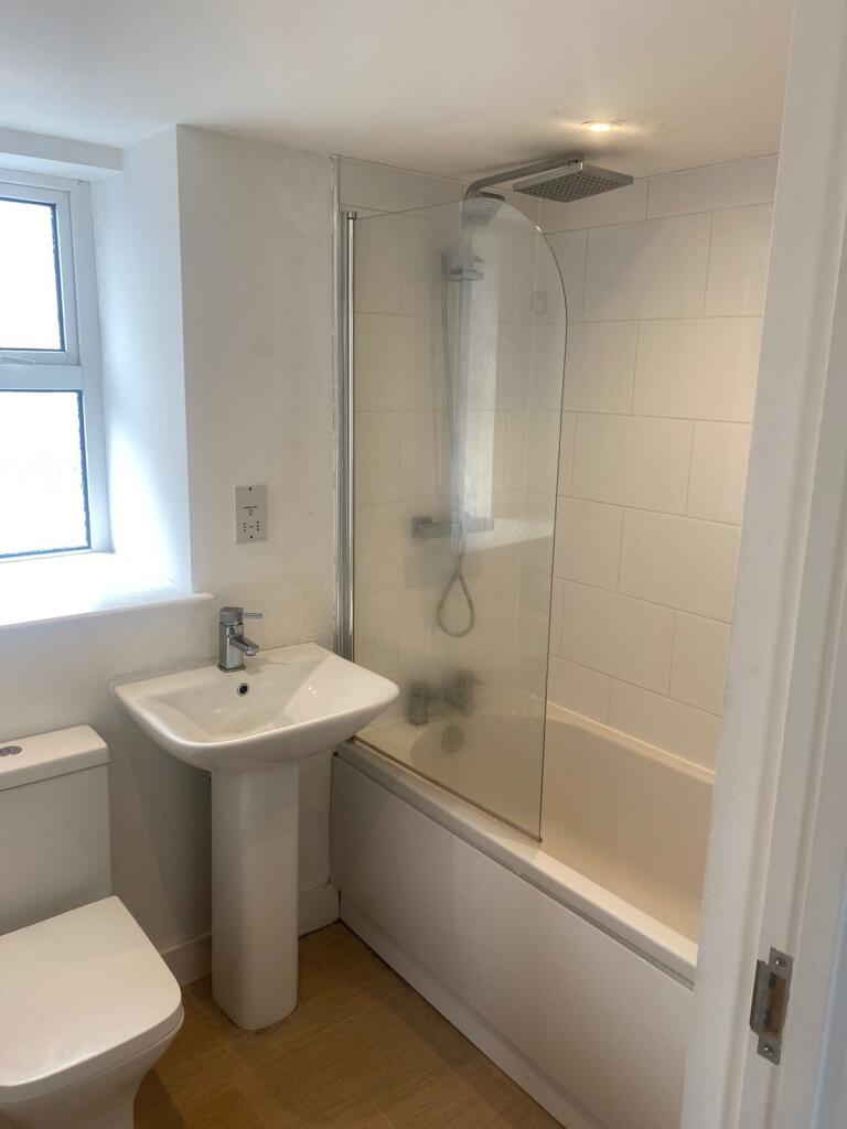 Bright, modern bathroom with a bathtub and over...