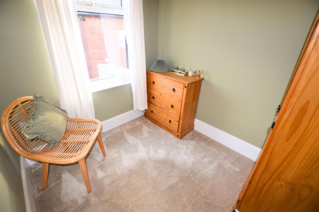 A cozy single bedroom featuring soft carpeting,...