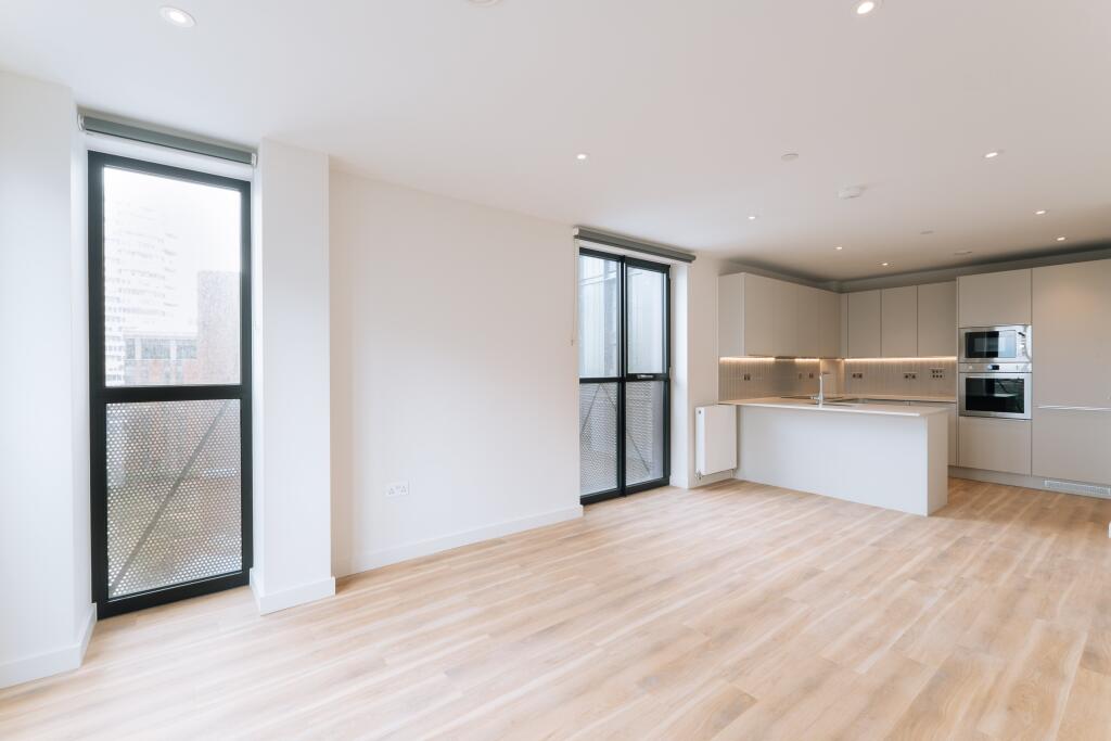 Step into a world of elegance with this open-concept kitchen and living area, bathed in natural light.