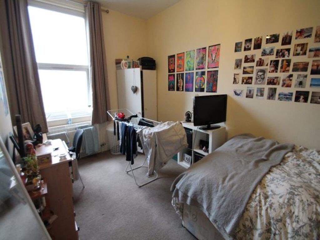 A well-lit, tidy bedroom featuring a comfortabl...