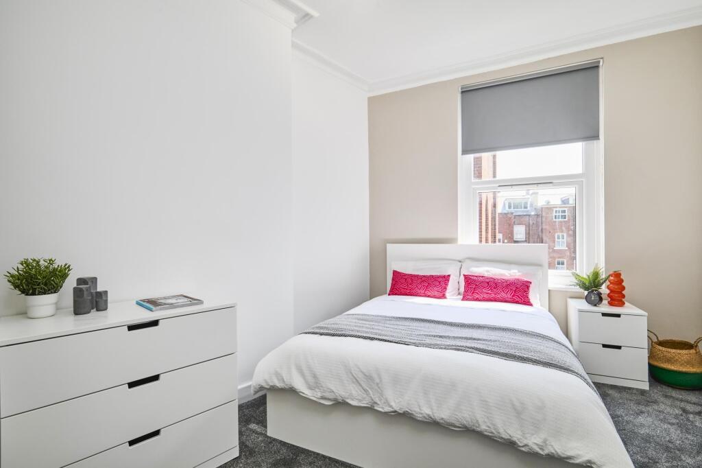 A bright and tidy bedroom featuring a comfortab...