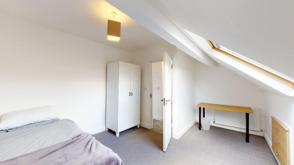 Bright single bedroom featuring a slanted ceili...