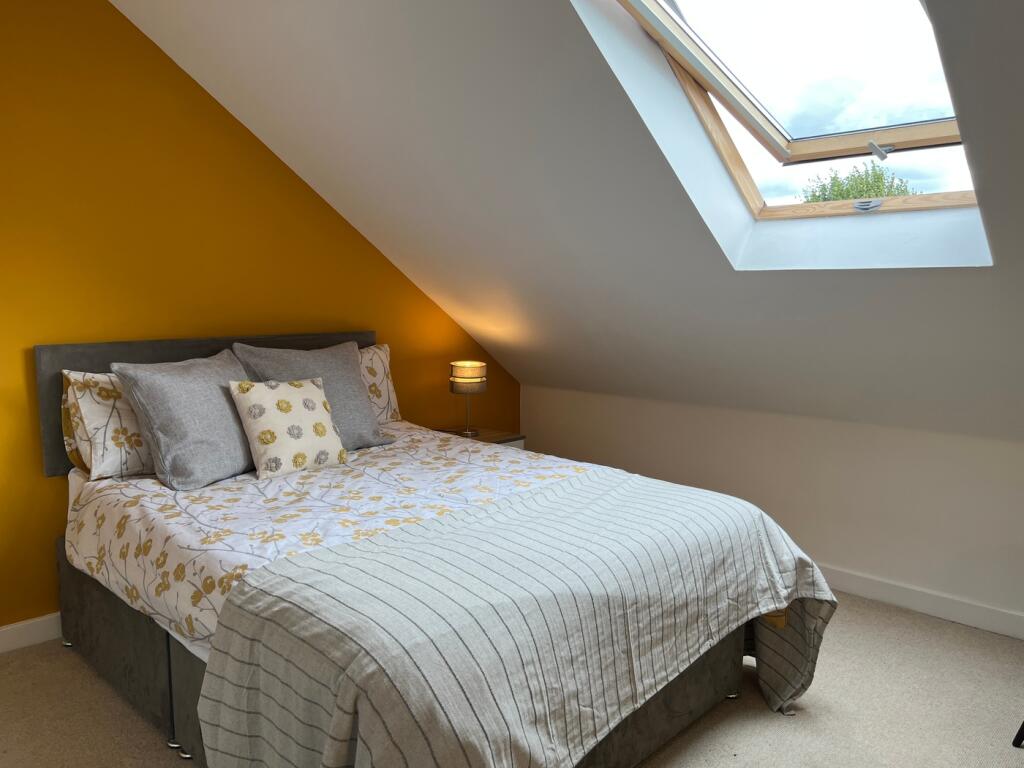 A bright and inviting double bedroom with a coz...