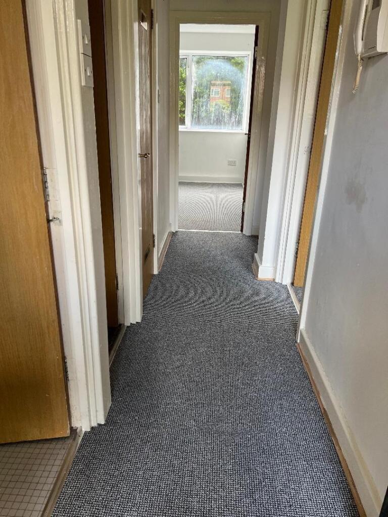 A tidy hallway with neutral carpeting extending...
