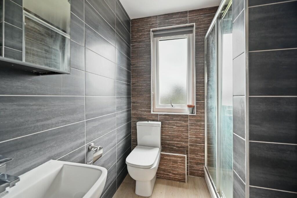 A modern bathroom featuring sleek dark wall til...