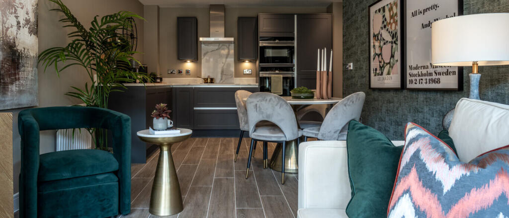 Modern open-plan kitchen and living area with grey cabinets, light grey seating and wall art with de