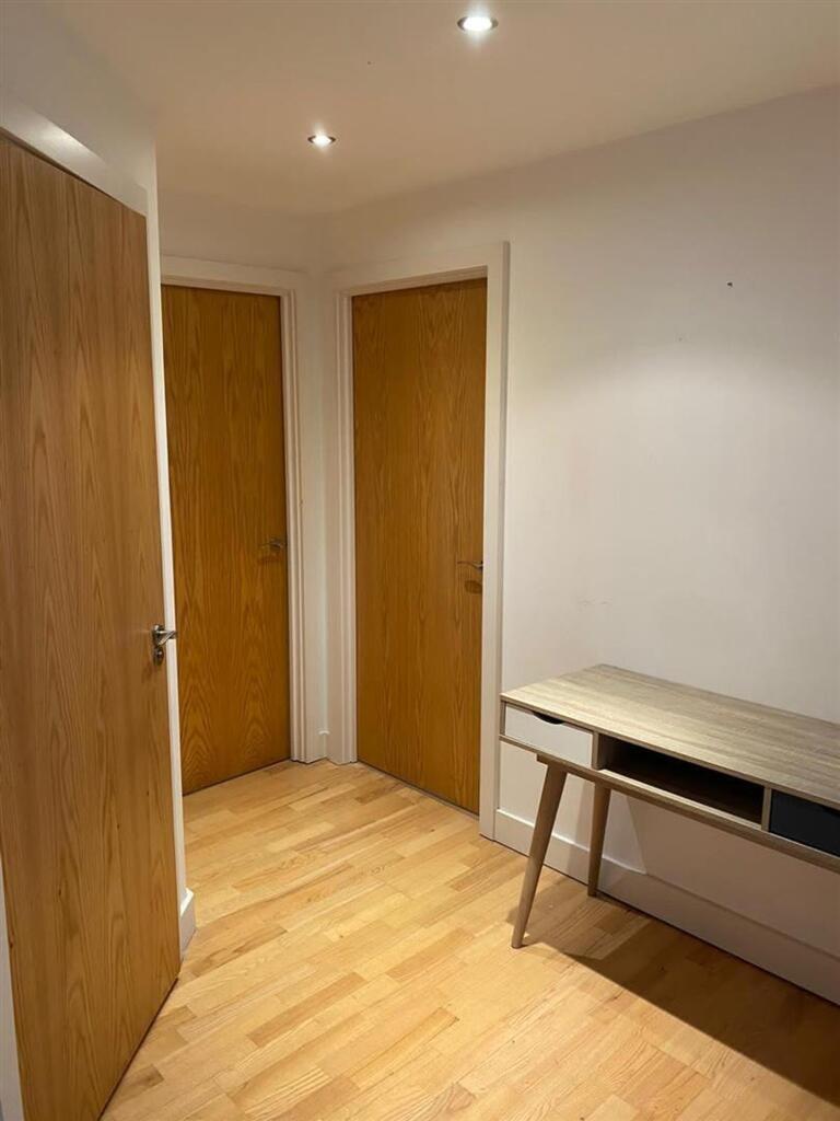 A clean, bright hallway with wooden flooring, t...