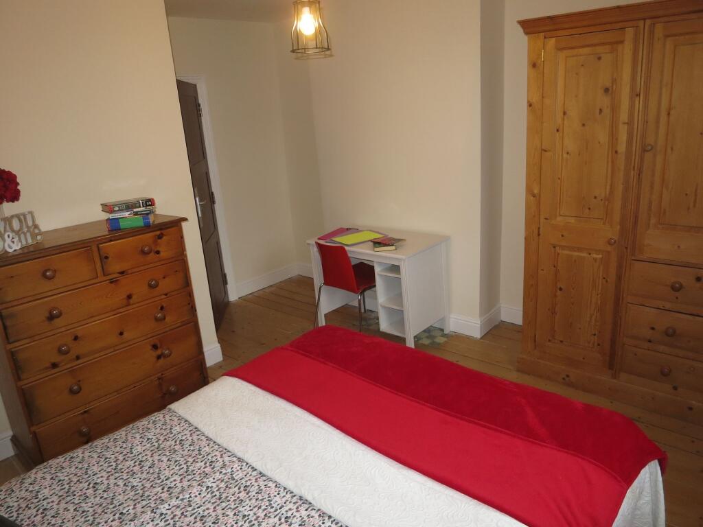 A cozy bedroom featuring wooden furniture, incl...