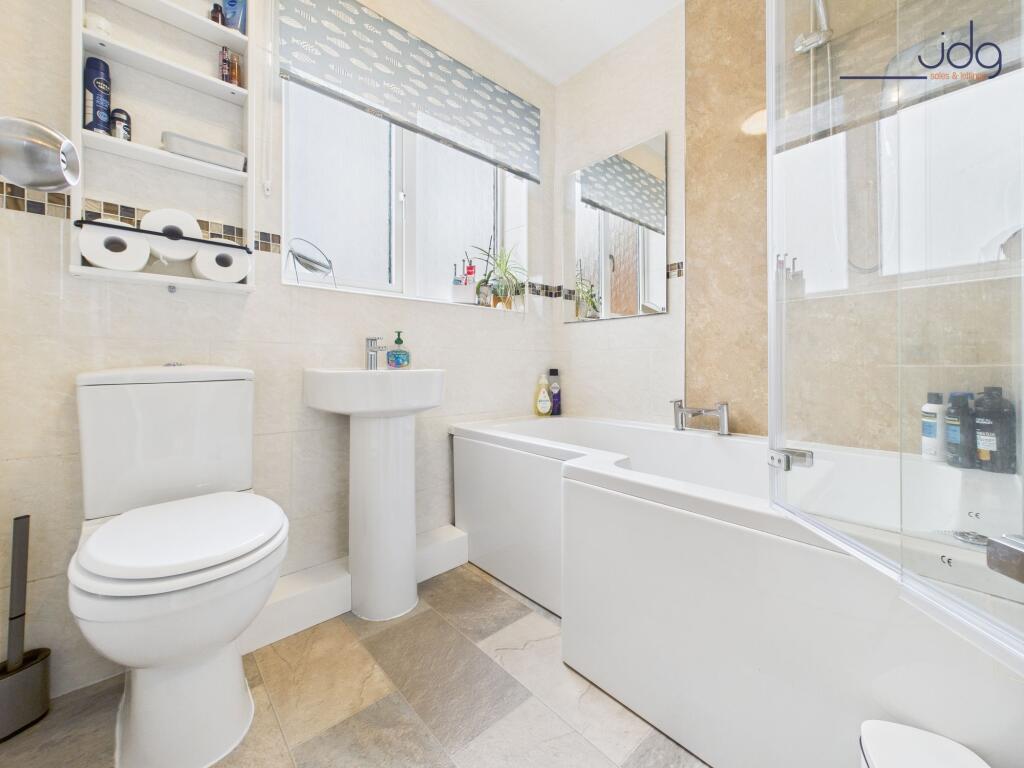 A white three-piece suite, including a P-shaped shower bath with overhead shower.