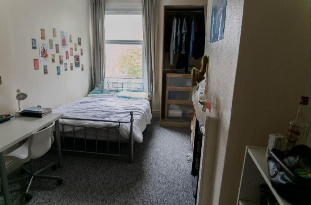 Cozy single bedroom with a large window providi...
