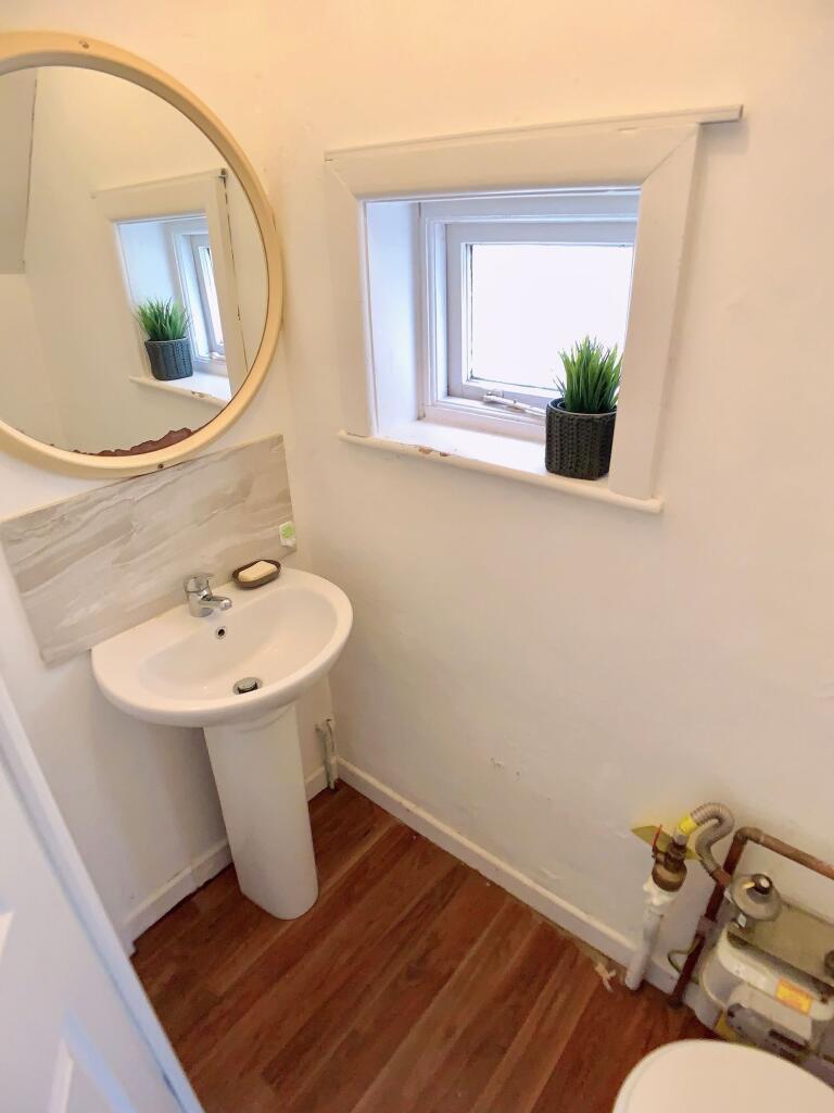 A compact bathroom featuring a small pedestal s...
