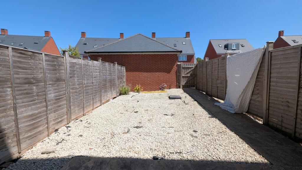 Sunny low-maintenance rear garden with pale gra...