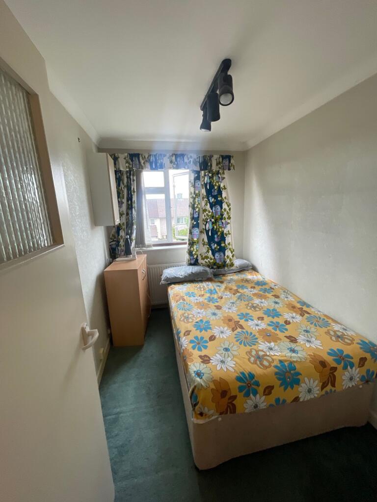 A cozy single bedroom featuring a floral bedspr...