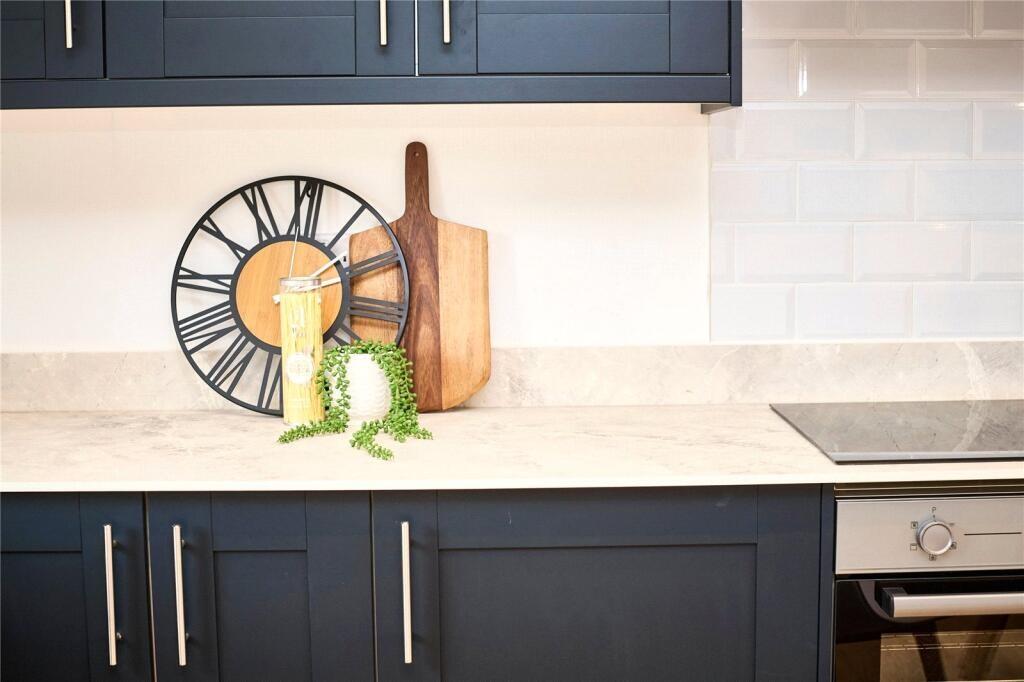 Modern kitchen featuring sleek navy cabinetry, ...