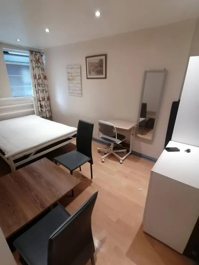 A tidy, well-lit single bedroom featuring woode...