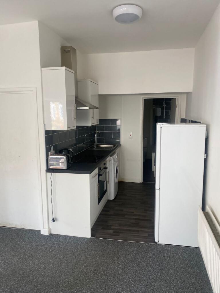 A compact, modern kitchen with white cabinetry,...