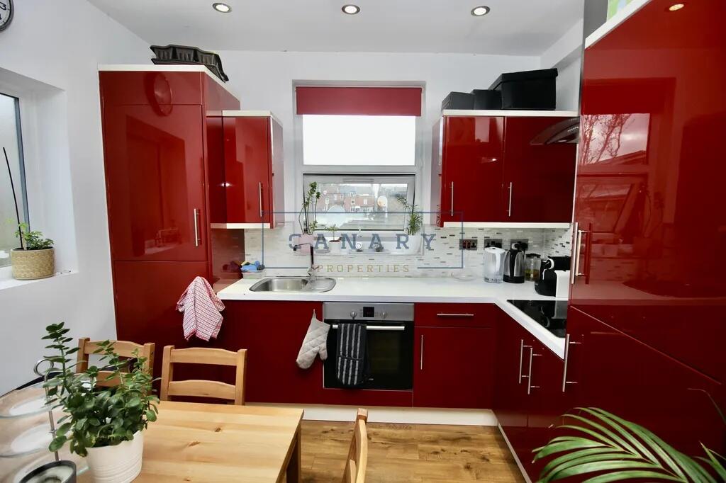 Bright modern kitchen featuring glossy red cabi...