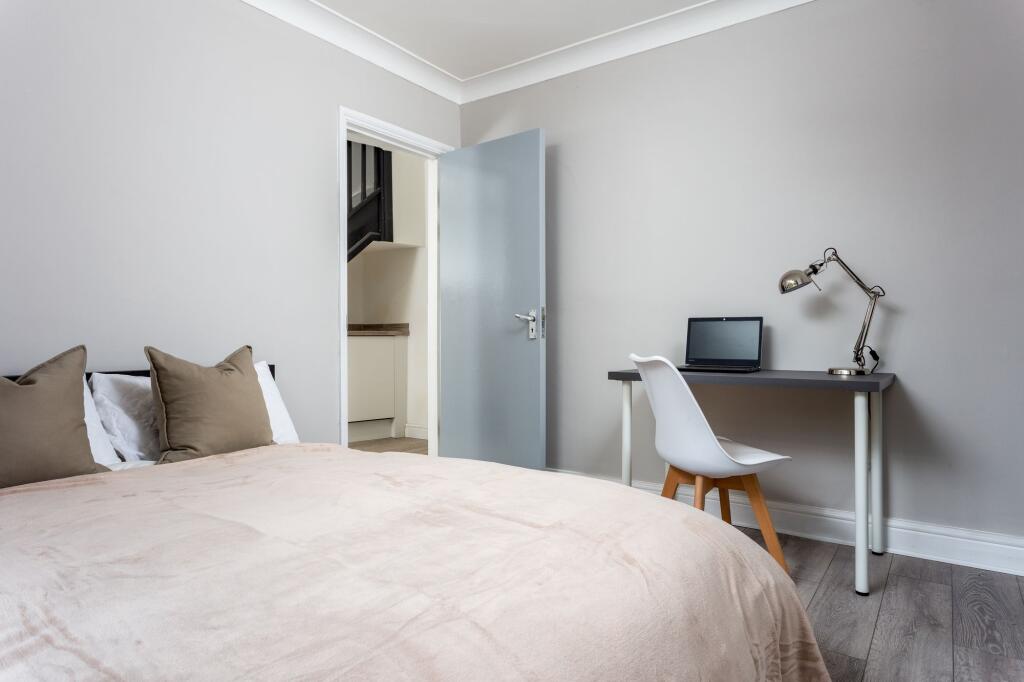 A cozy double bedroom featuring a soft beige be...