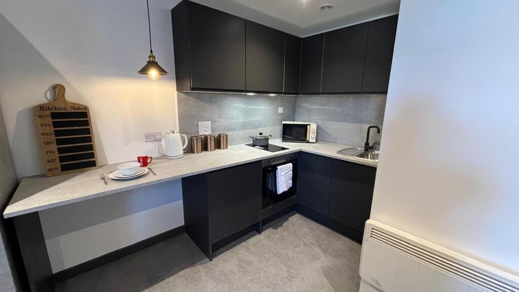 A modern compact kitchen featuring sleek black ...