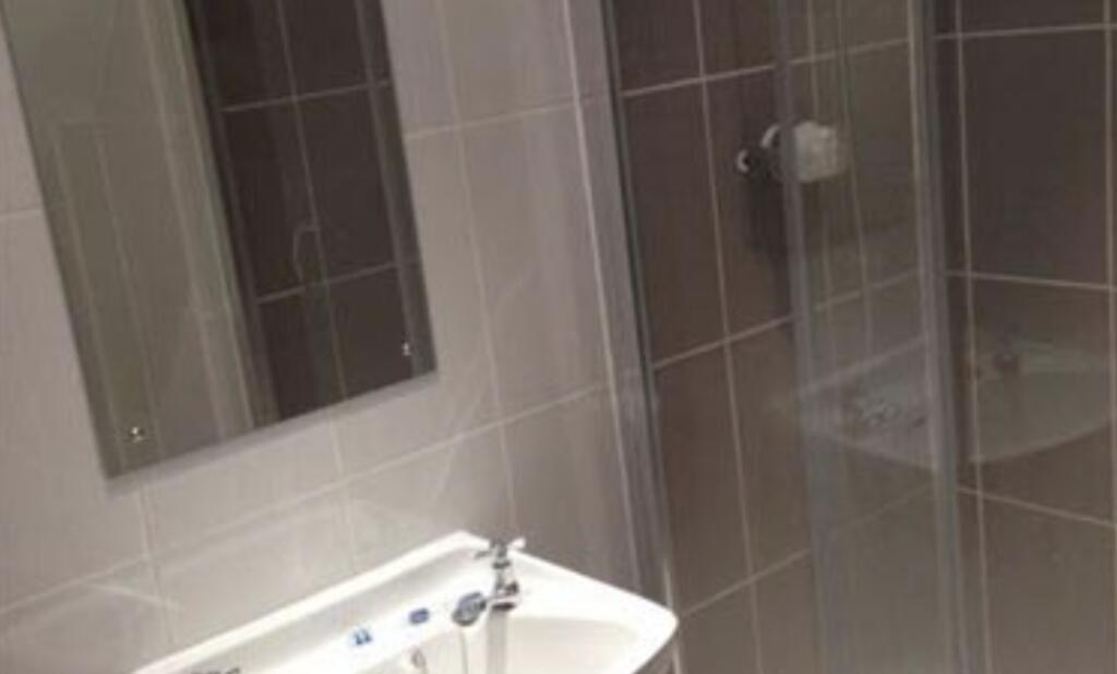 Modern tiled bathroom with a wall-mounted mirro...